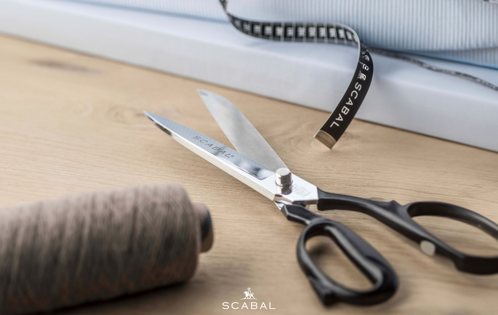 Schere, Maßband und Stoffrolle von Scabal – Werkzeuge für hochwertige Masskonfektion aus edlen Materialien. Schere, Massband und Stoffrolle von Scabal – Werkzeuge für hochwertige Masskonfektion aus edlen Materialien.