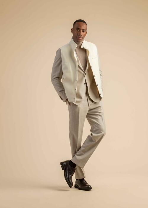 Eleganter Beige-Anzug mit weisser Weste – moderner Herren-Layering-Look Herrenanzug in hellem Beige mit Rollkragenpullover und weisser Weste im modernen Layering-Stil.