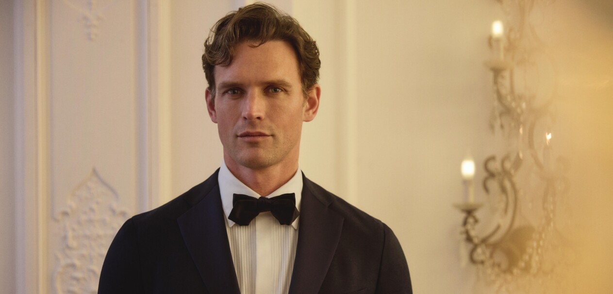 Dieser Hochzeitslook aus der Scabal Jazz Kollektion verbindet sommerliche Leichtigkeit mit festlichem Stil. Das pinke Sakko mit feiner Textur, kombiniert mit einer tief bordeauxfarbenen Hose, schafft einen mutigen und dennoch raffinierten Auftritt – ideal für besondere Anlässe.