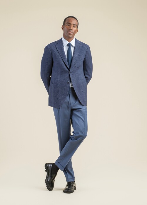 Eleganter Herrenlook aus der Scabal Frühling Sommer 2026 Kollektion mit dunkelblauem Jazz Sakko, gestreiftem Hemd, Krawatte und passender blauer Hose.