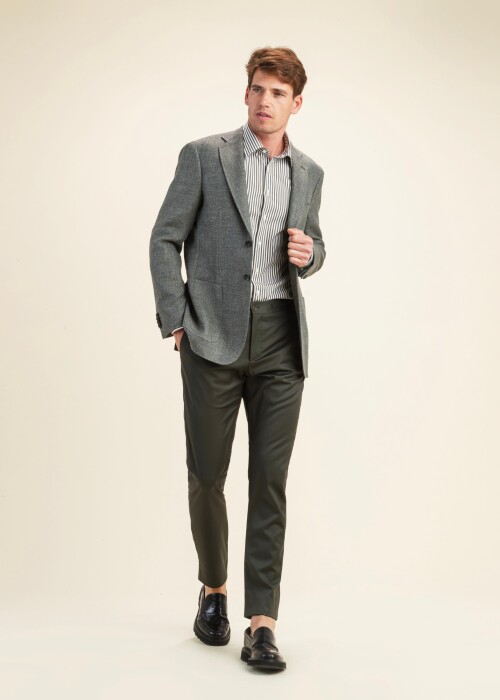 Herrenoutfit aus der Scabal Frühling Sommer 2026 Kollektion mit dunkelgrauem Sakko aus der Riviera Trend Linie, gestreiftem Hemd und olivgrüner Hose.