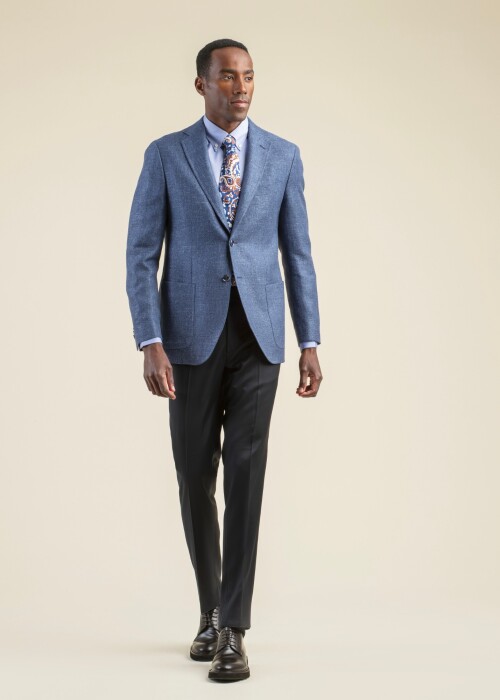 Eleganter Herrenlook aus der Scabal Frühling Sommer 2026 Kollektion mit blauem Sakko aus der Jazz Kollektion, kombiniert mit schwarzer Hose und Paisley-Krawatte.