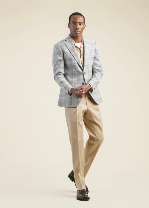 Scabal Riviera Trend Sakko mit grauem Karomuster, kombiniert mit beigem Overshirt und Hose – Look aus der scabal frühling sommer 2026 Kollektion.