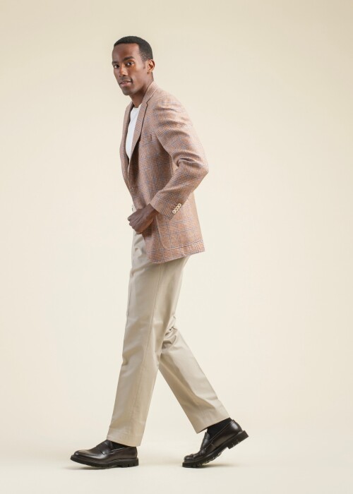 Herrenoutfit aus der Scabal Frühling Sommer 2026 Kollektion mit kariertem Sakko in Orange-Beige aus der Riviera Trend Linie und beigefarbener Hose.