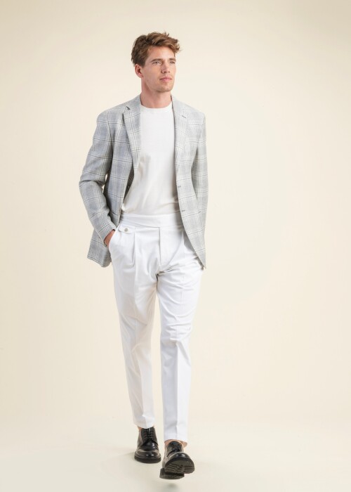 Herrenoutfit aus der Scabal Frühling Sommer 2026 Kollektion mit hellgrauem Karo-Sakko aus der Riviera Trend Linie und weisser Bundfaltenhose.