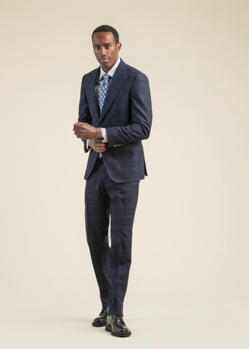 Business-Anzug aus der Scabal Frühling Sommer 2026 Kollektion in dunklem Karomuster aus der Riviera Trend Linie, kombiniert mit gestreiftem Hemd und gemusterter Krawatte.