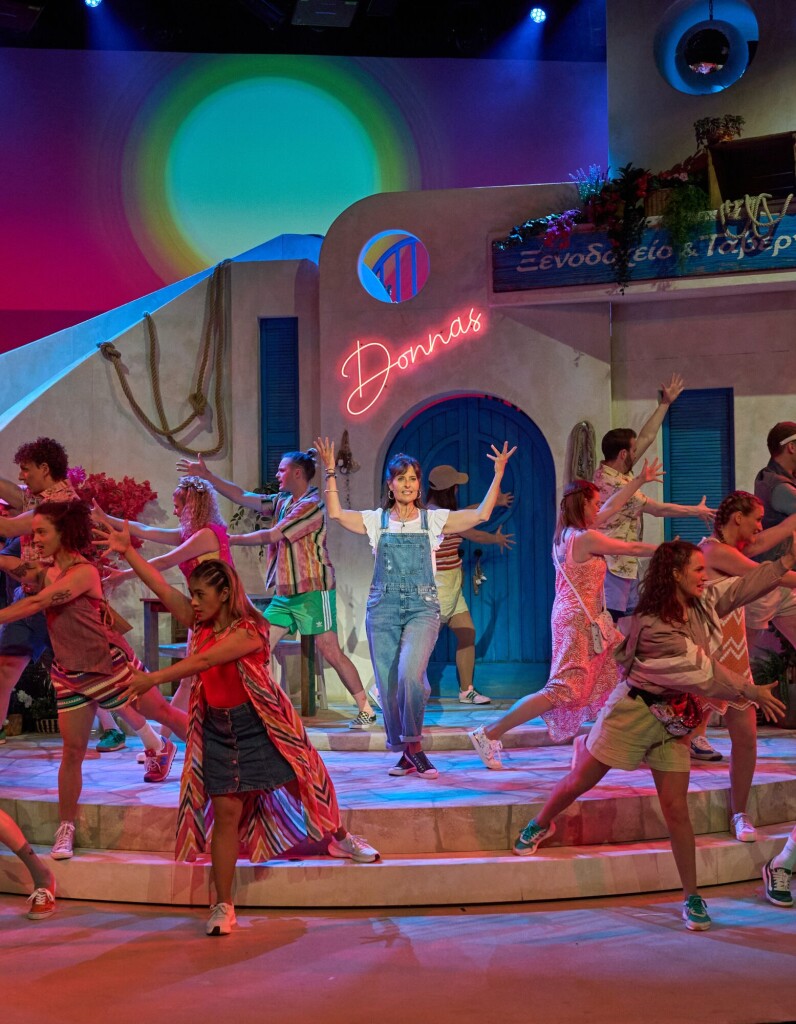 Mamma Mia das Musical auf Schweizerdeutsch mit Ensemble vor der Donnas Kulisse und farbenfroher Bühnenbeleuchtung fotografiert von René Tanner