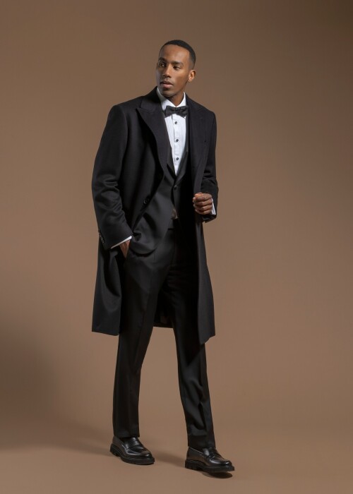 Schwarzer Scabal Mantel über einem klassischen Smoking aus der Herbst-Winterkollektion 2026, individuell massgeschneidert von Die Manufaktur – deine Schneiderei in St. Gallen.